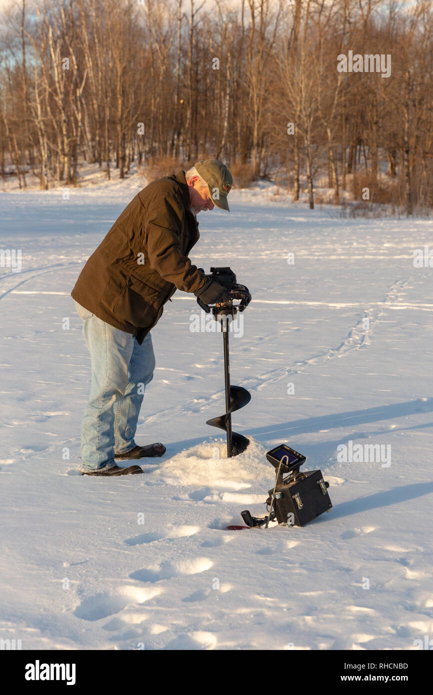 Fisherman using an ice auger to drill a hole in the ice Stock