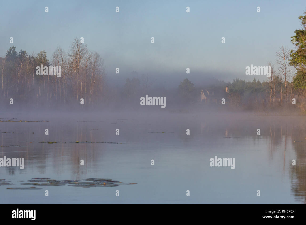 The autumn fog begins to lift revealing a north woods home on the shores of a wilderness lake in northern Wisconsin. Stock Photo