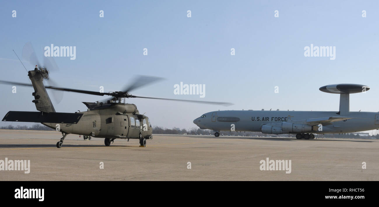 An Oklahoma Army National Guard UH-60M Blackhawk helicopter with rotors turning awaits the take off of an Air Force E-3 Sentry during a SENTRY REX 19-01 exercise period Jan. 15, 2019, Tinker Air Force Base, Oklahoma. The exercise focused on rescuing a simulated downed aircrew member in a joint-service environment. (U.S. Air Force photo/Greg L. Davis) Stock Photo