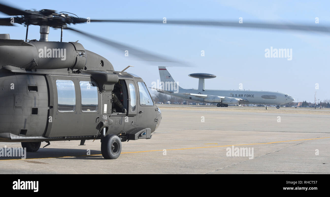 An E-3 Sentry of the 552nd Air Control Wing lines-up on the main runway while an Oklahoma Army National Guard UH-60M Blackhawk of the 1-244th Aviation Regiment prepares to take-off for a SENTRY REX 19-01 mission Jan. 15, 2019, Tinker Air Force Base, Oklahoma. SENTRY REX 19-01 was a multi-service exercise run out of Tinker AFB from Jan. 14-18 focusing on combined force rescue operations of downed aircrew. (U.S. Air Force photo/Greg L. Davis) Stock Photo