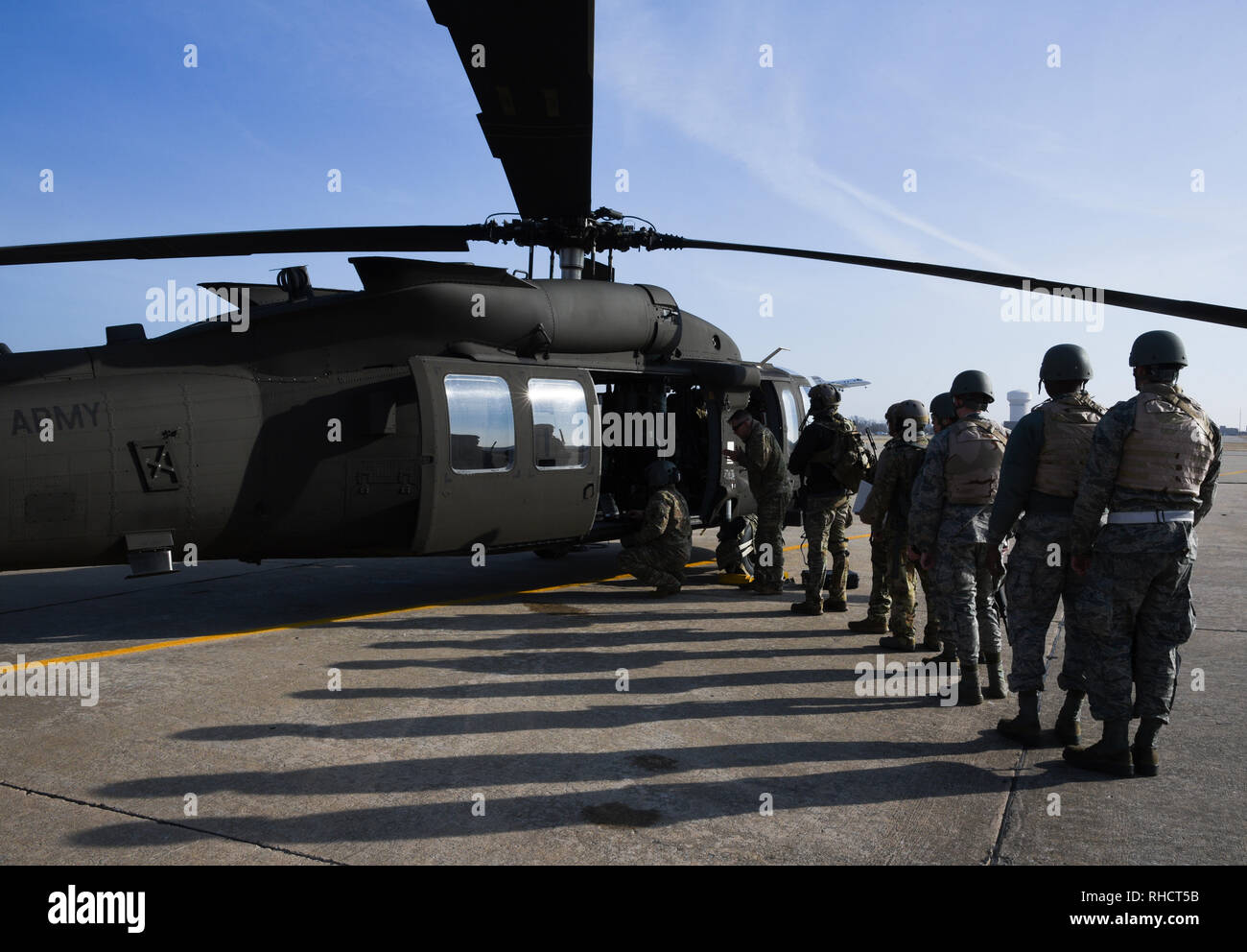 Long shadows are cast upon the flight line as members of the 137th Special Operations Wing, Oklahoma Air National Guard, line-up to board an Oklahoma Army National Guard UH-60M Blackhawk at Tinker Air Force Base, Oklahoma during SENTRY REX 19-01 exercise on Jan. 15, 2019. The training exercise allowed the special operators to be inserted in a defended landing-zone with the goal of rescuing a downed aircrew member. (U.S. Air Force photo/Greg L. Davis) Stock Photo