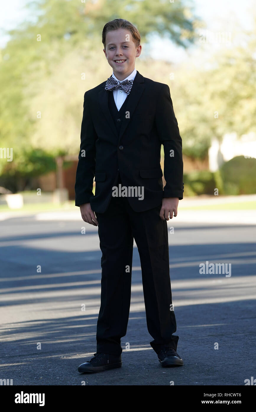 A boy in a suit with a bow tie poses for a portrait. Stock Photo