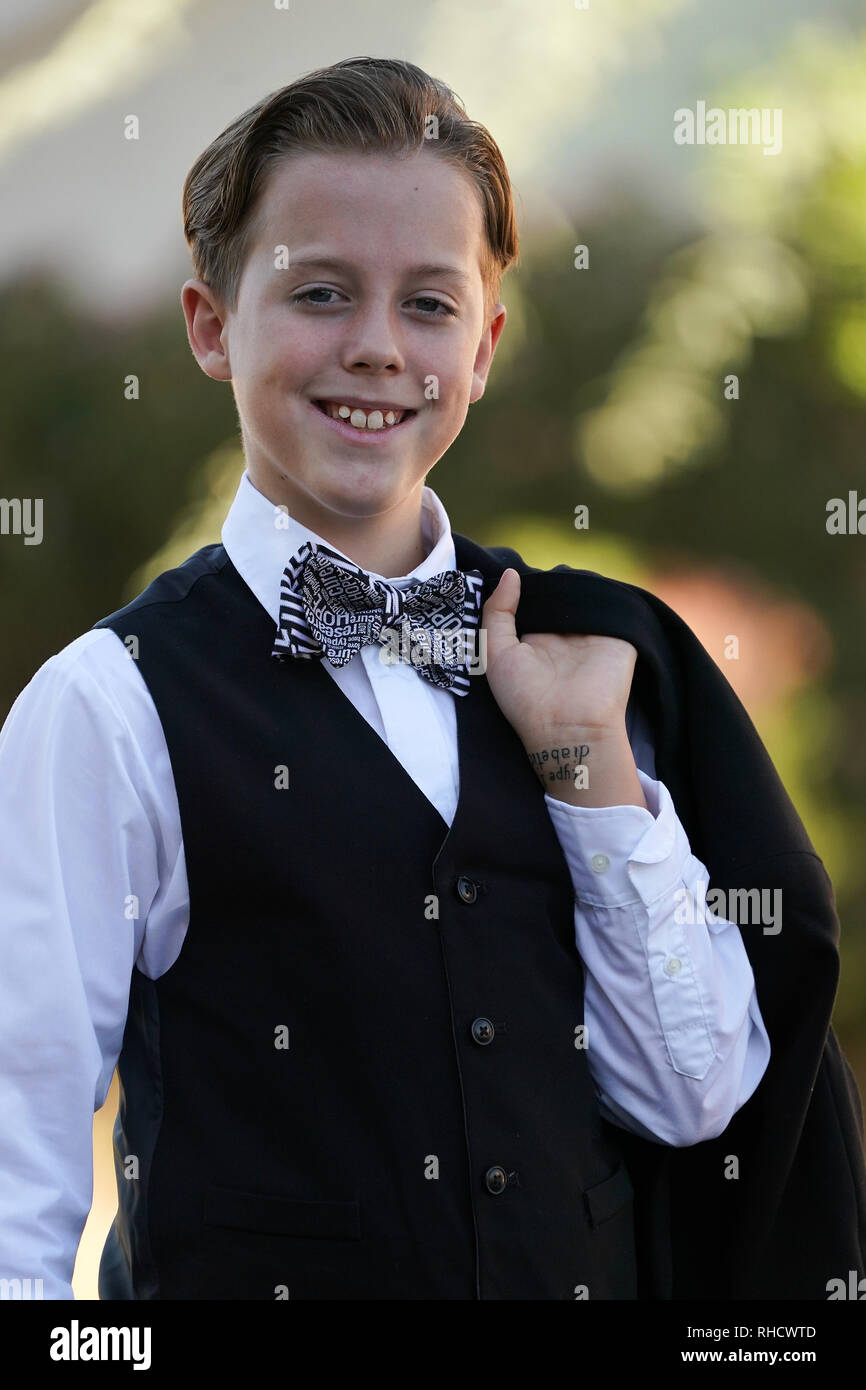 A boy in a suit with a bow tie poses for a portrait. Stock Photo