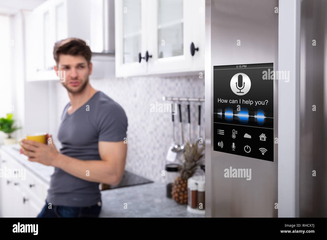 Man Standing Near Oven With Voice Recognition Function In Kitchen Stock Photo
