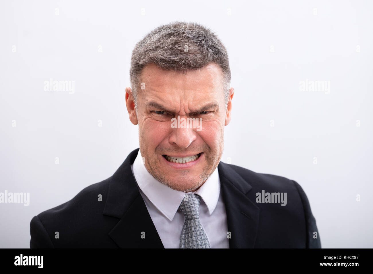 An Angry Mature Businessman Clenching His Teeth Against White Background Stock Photo