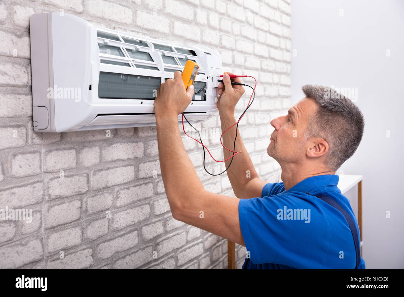 Male Electrician Checking Air Conditioner With Digital Multimeter Stock Photo
