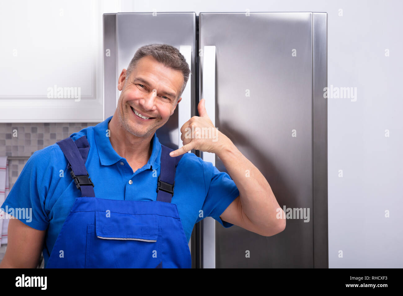 Happy Mature Male Technician Gesturing Call Sign Stock Photo