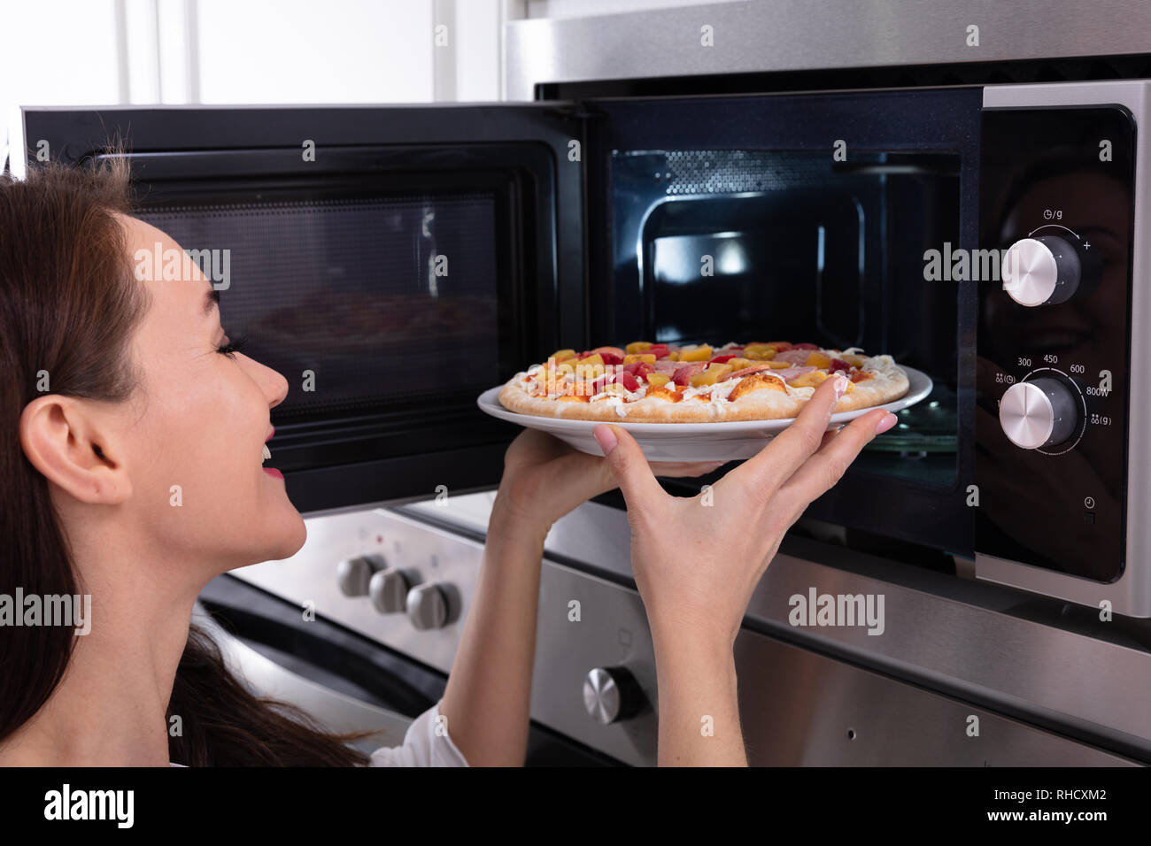 https://c8.alamy.com/comp/RHCXM2/close-up-of-a-happy-woman-baking-pizza-in-microwave-oven-RHCXM2.jpg