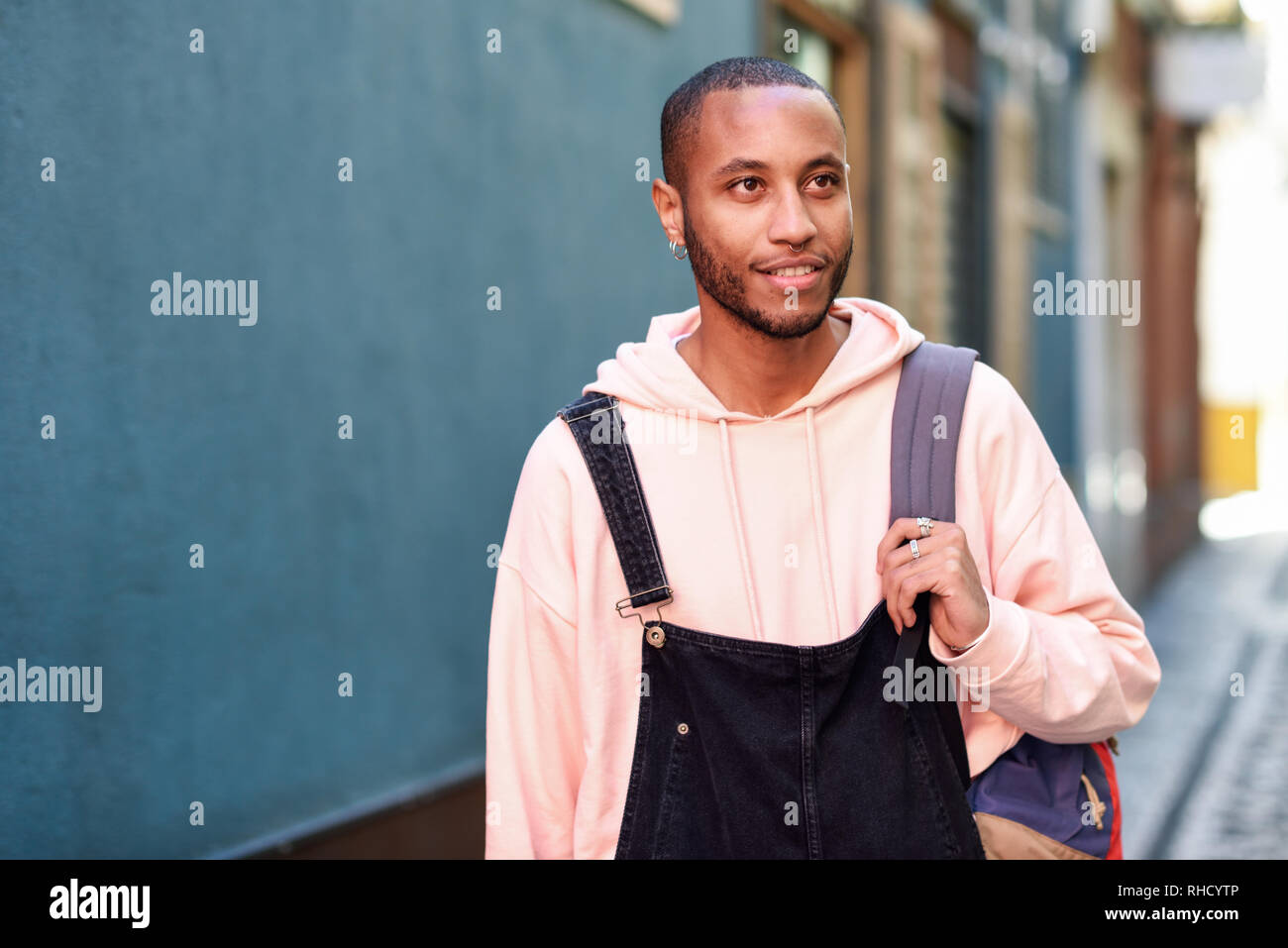 Young black man walking smiling down the street. Stock Photo