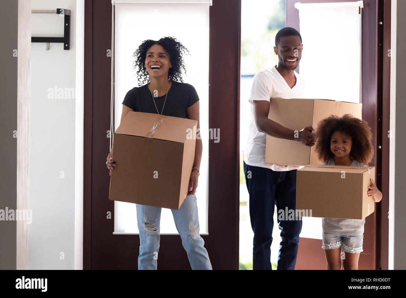 Excited black family entering new house holding boxes moving in Stock Photo