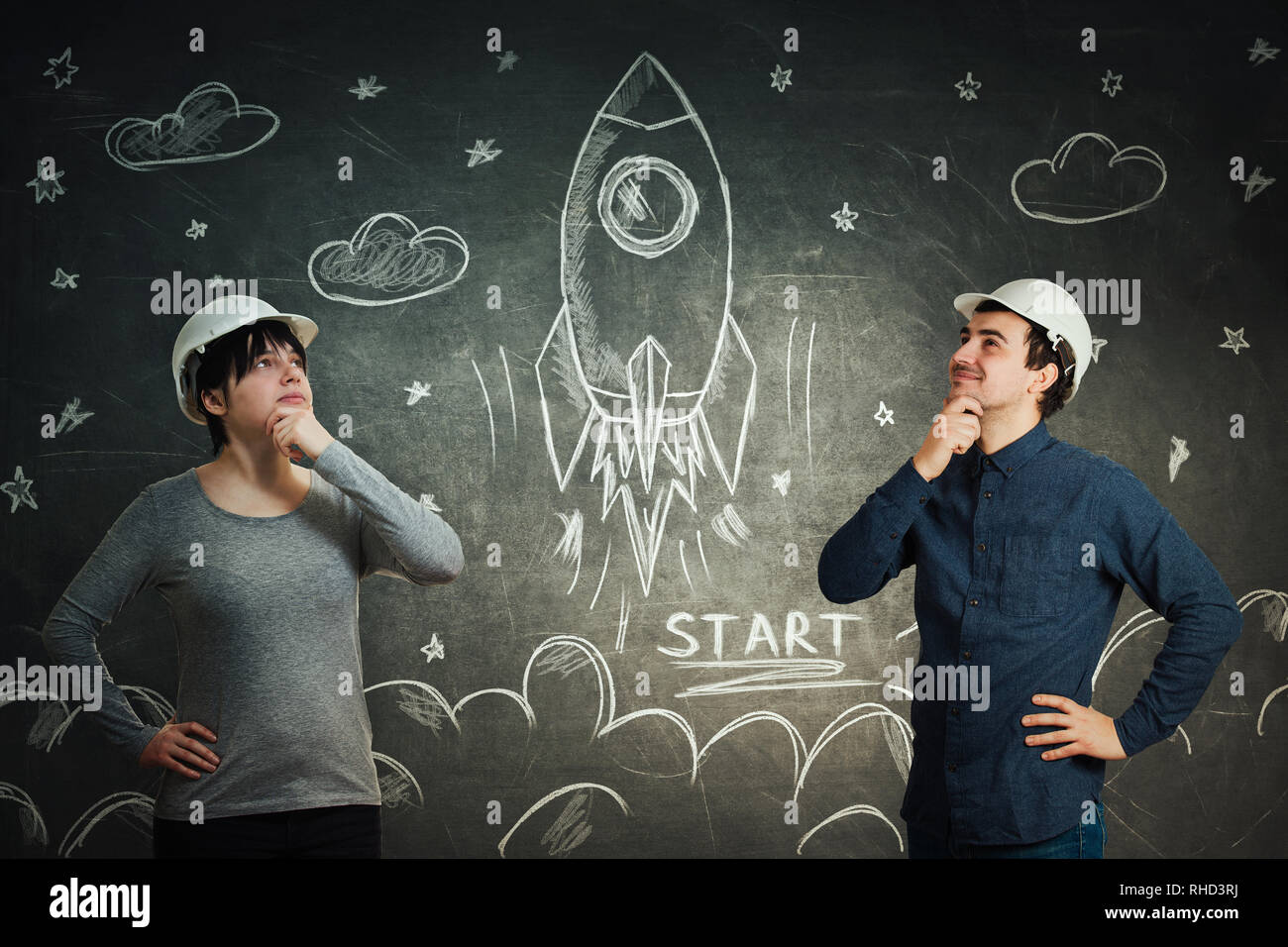 Engineers scientists man and woman sharing thoughts together for starting a rocket space ship in cosmos drawing sketch on blackboard. Idea exchange pa Stock Photo