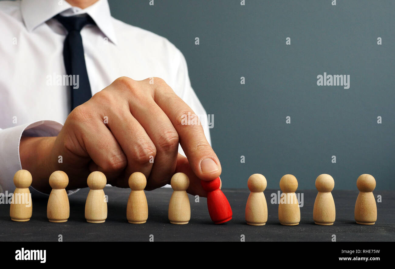 Recruiter choosing one figurine from the crowd. Talent management and hiring. Stock Photo