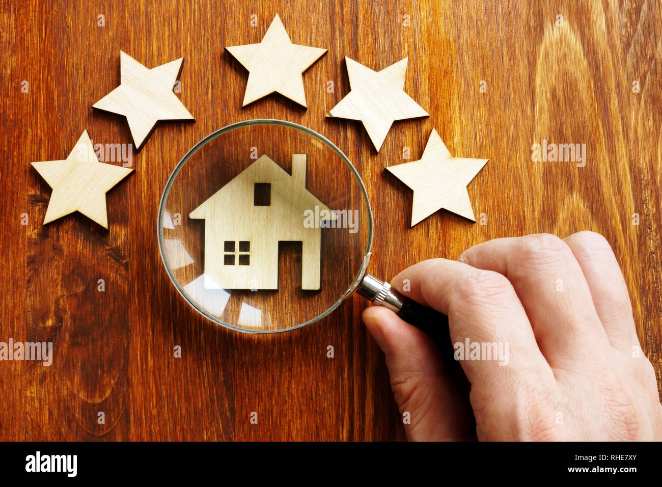 Property assessment concept. Hand holds magnifier, model of home and 5 stars. Stock Photo