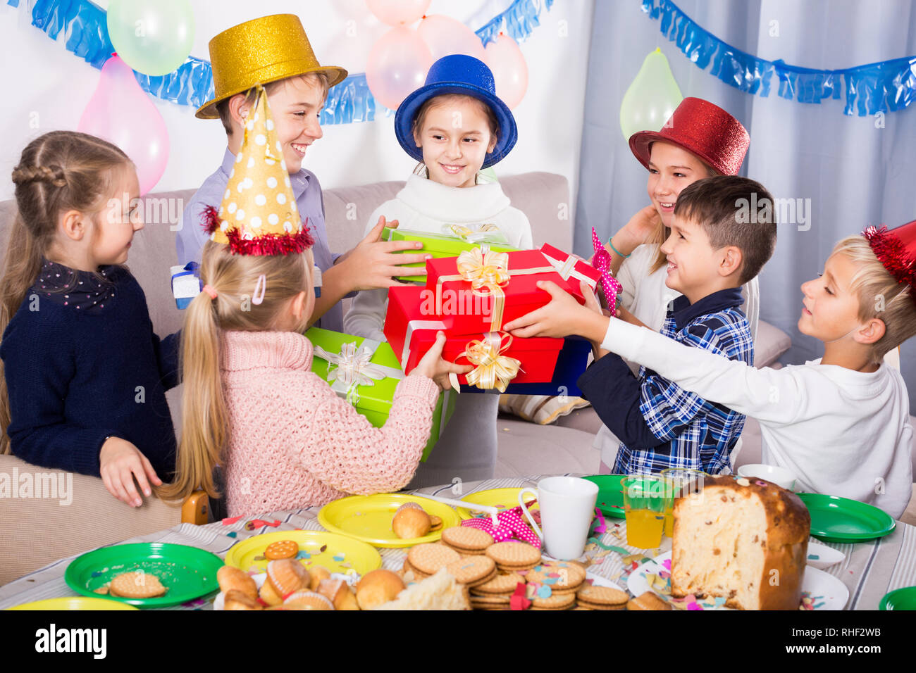 Satisfied children presenting gifts to girl during birthday party Stock ...