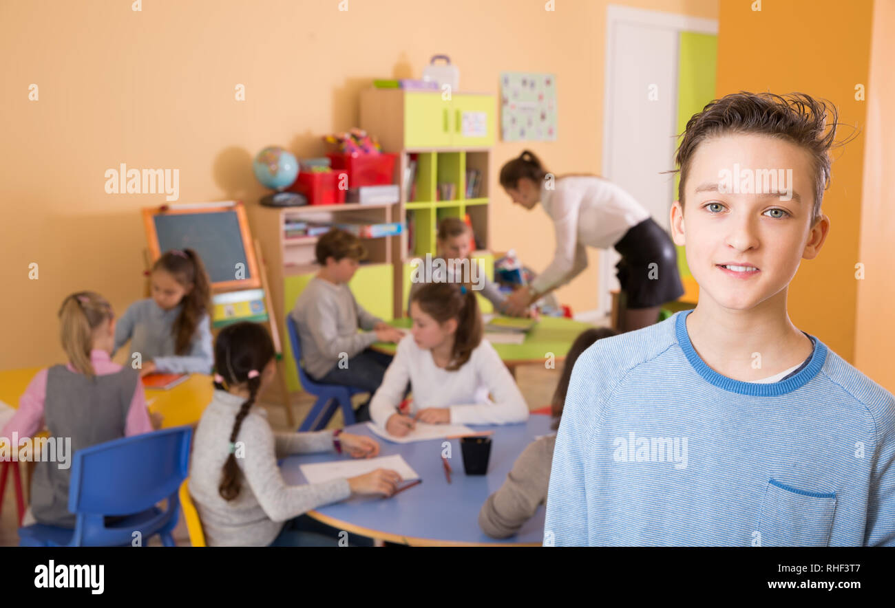 Smiling schoolboy standing, elementary age children drawing at class ...
