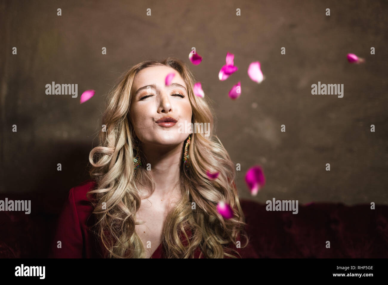 A young blonde woman with falling pink rose petals Stock Photo