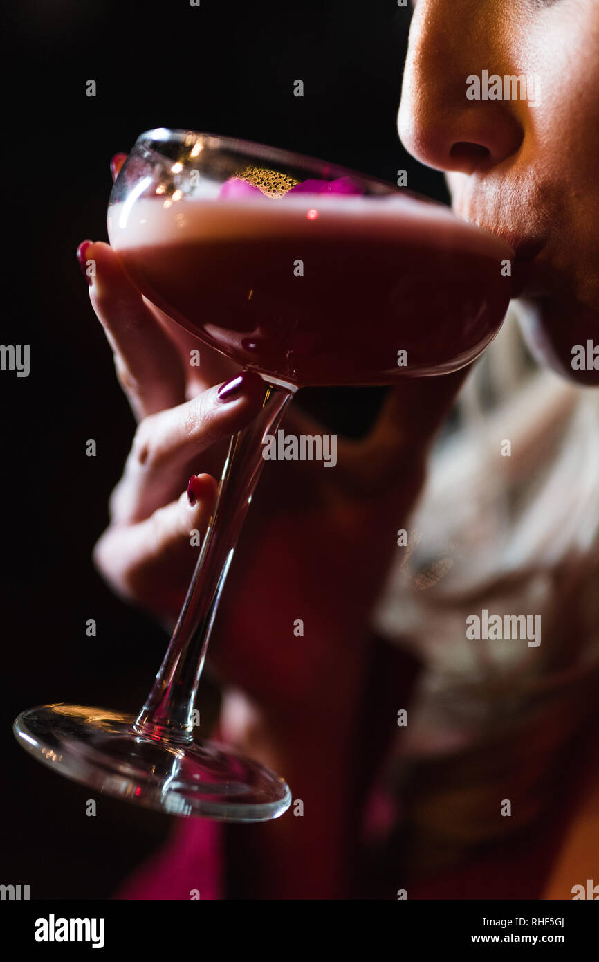 A young blonde woman drinks from a pink cocktail Stock Photo
