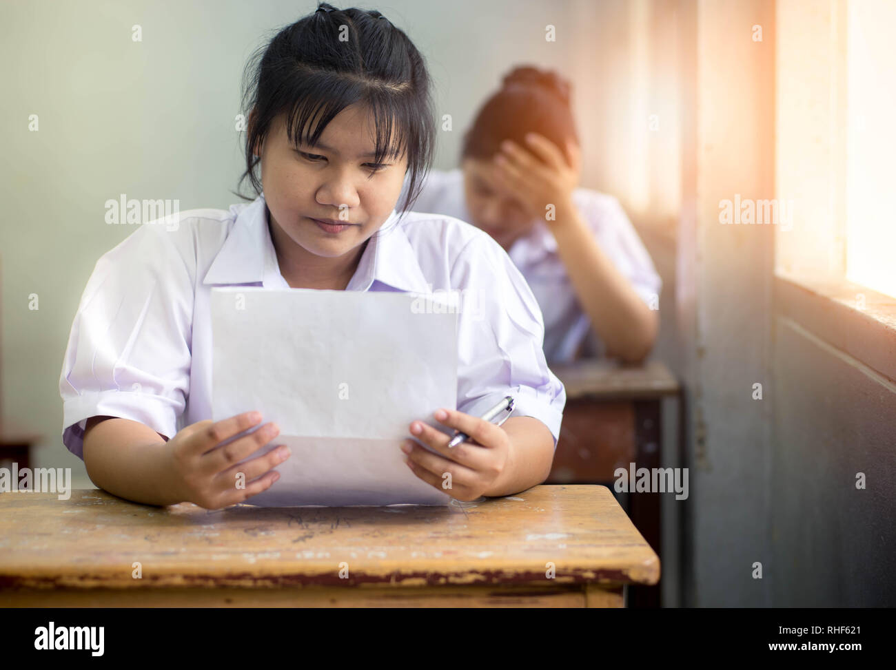 Portrait of young girl students writing the exam with smile. Stock Photo