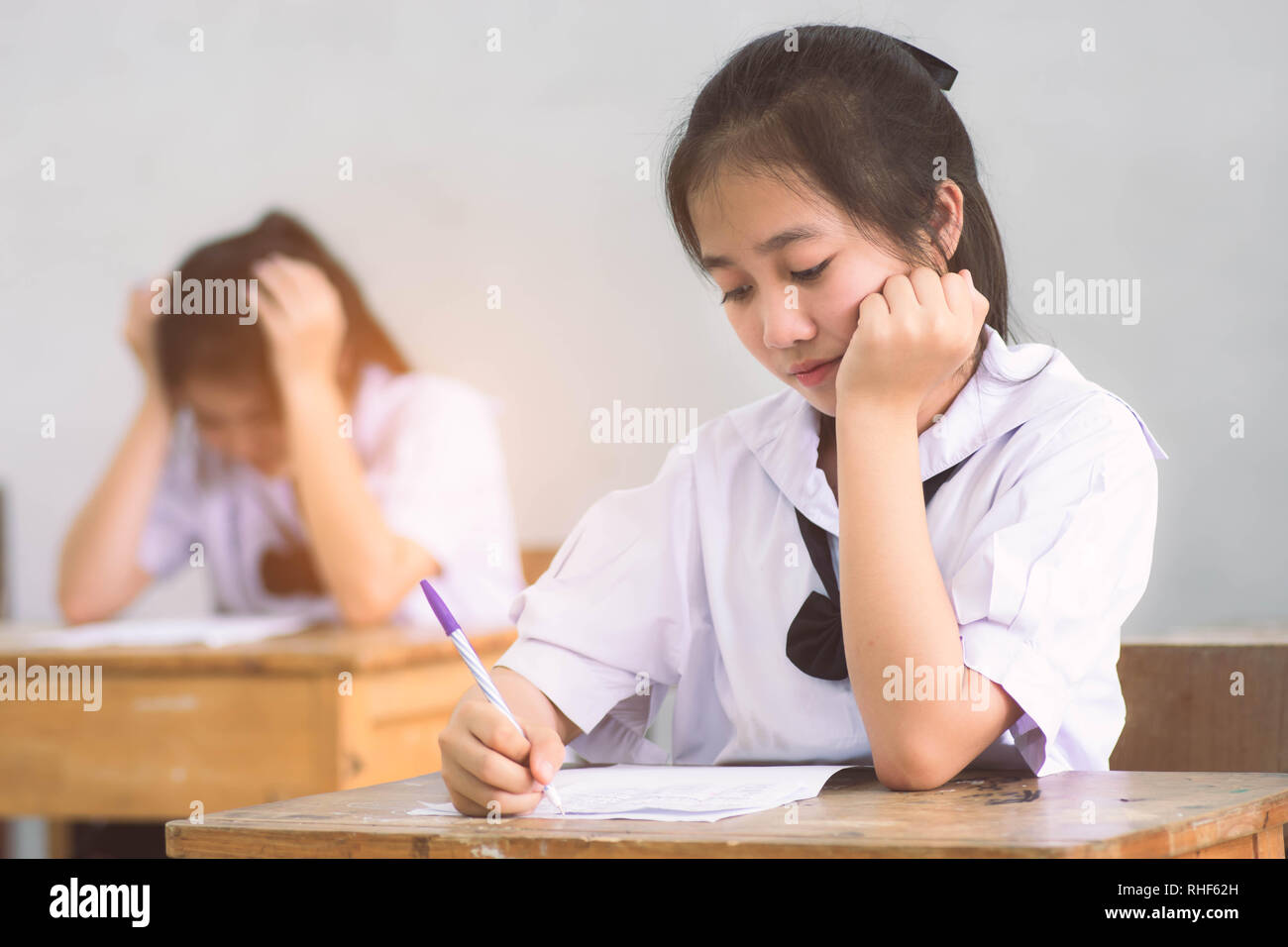 Smile young girl student reading and writing exam with not stress Stock