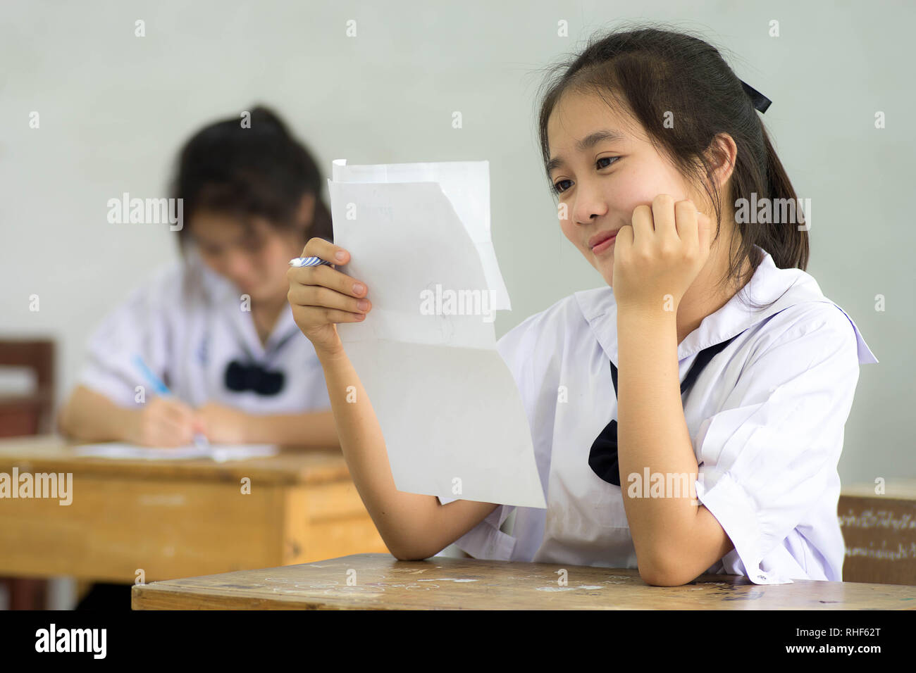 Smile young girl student reading and writing exam with not stress Stock
