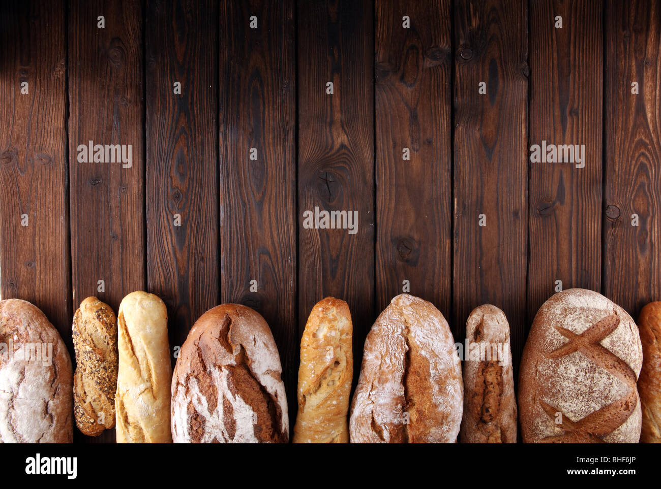 Assortment of baked bread and bread rolls on wooden table background ...