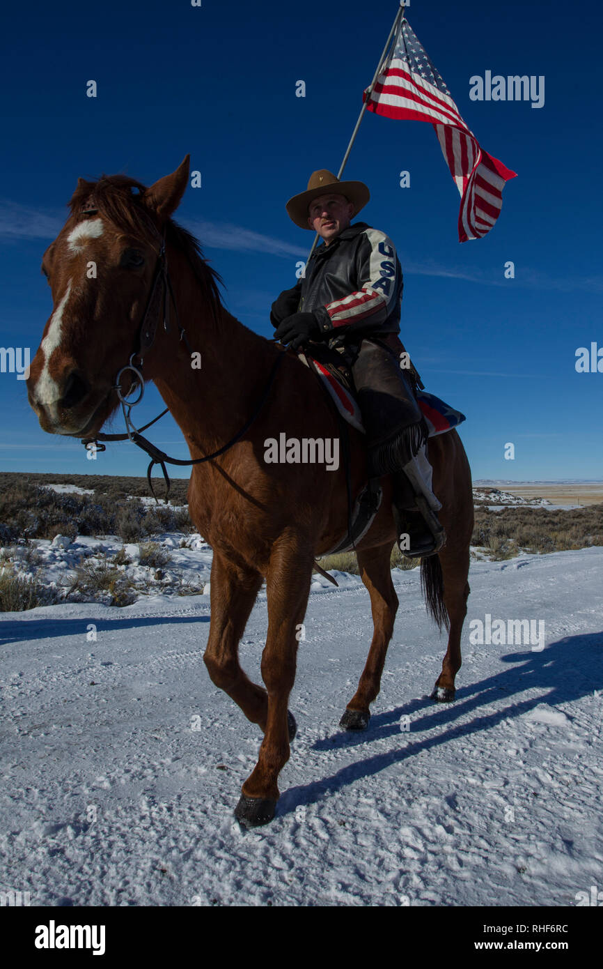 At the entrance gate to the Malheur NWR Field Station, Duane Ehmer rides by carrying an American flag during the 'Bundy Standoff' Stock Photo