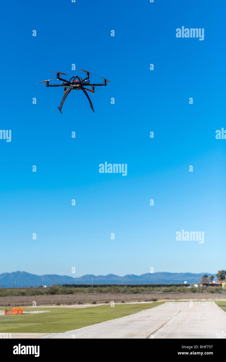 Professional drone flying over the airfield in hover Stock Photo