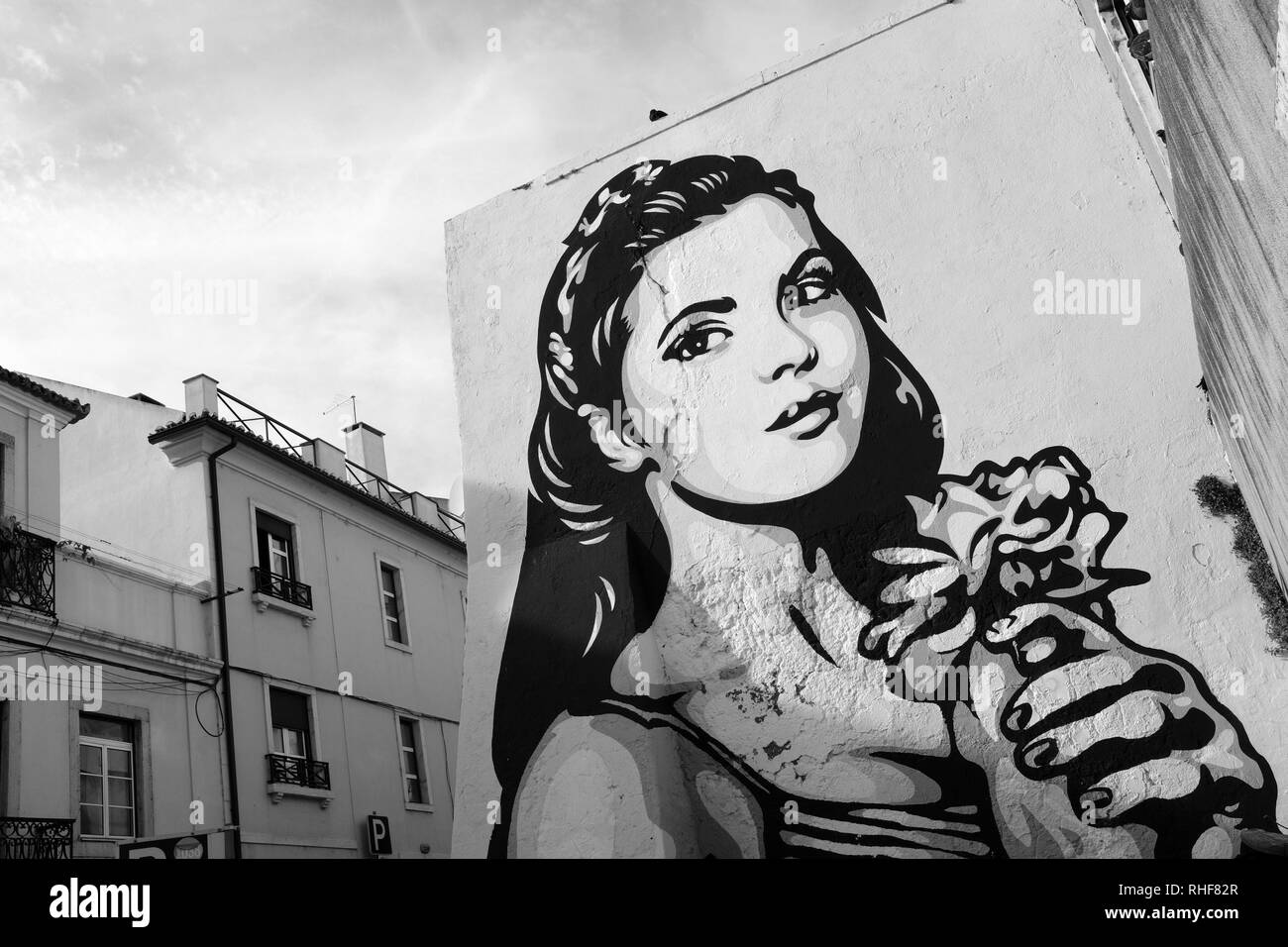 GRAFFITI STREET ART OF YOUNG GIRL HOLDING A BUNCH OF FLOWERS – LISBON PORTUGAL Stock Photo