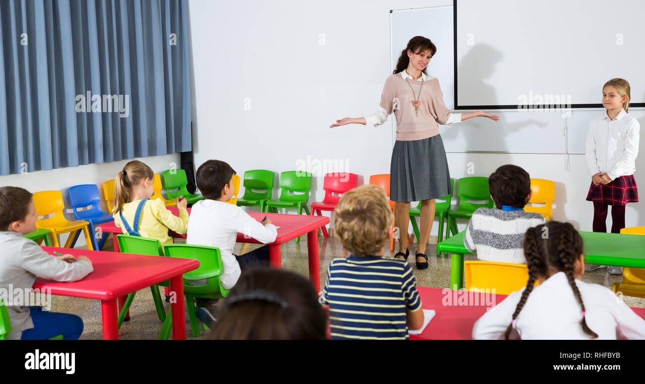 in front of school board Young female teacher standing in front of pupils near school board on  lesson, satisfied with answer of schoolgirl Stock Photo - Alamy