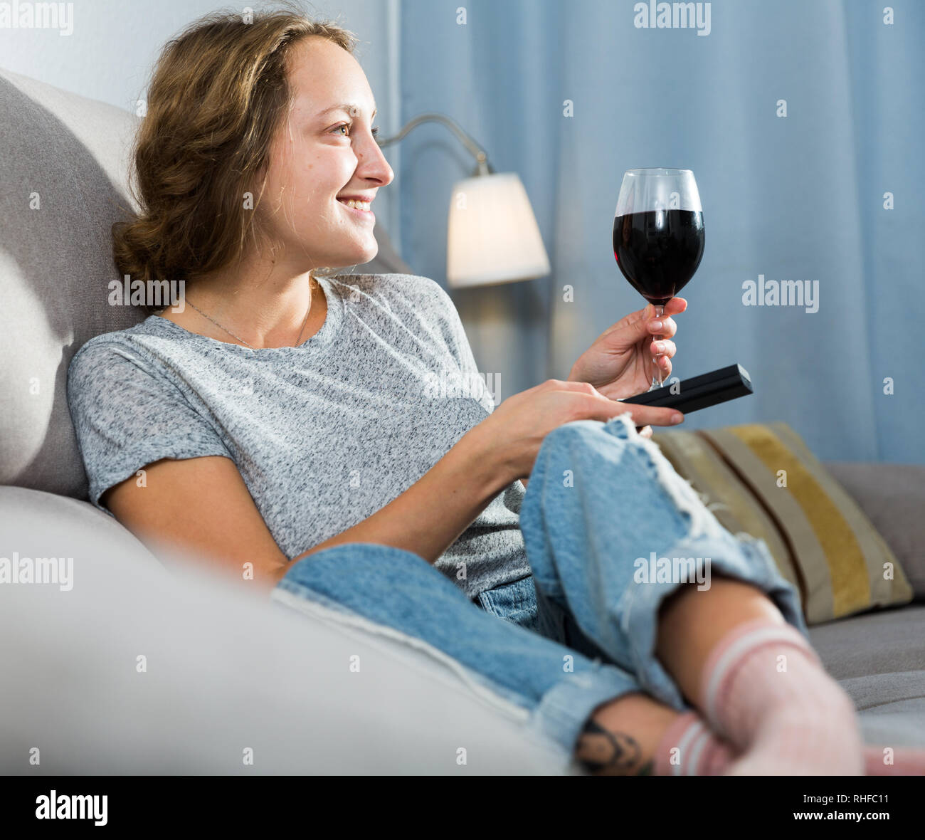 Young woman relaxing with glass of wine and watching TV at home Stock ...