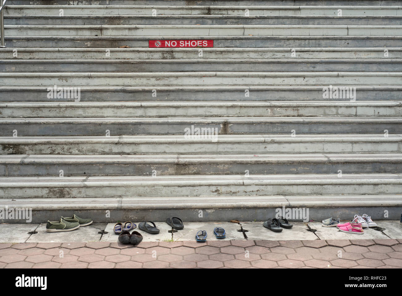 Steps of a stone stair to a temple with a red sign no shoes and shoes in front of the stairs Stock Photo