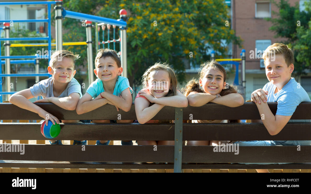 Glad children sitting on a bench at the playground Stock Photo - Alamy