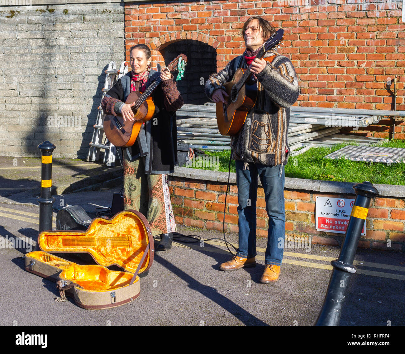 male guitarist and female guitarist or buskers performing on a public street Stock Photo