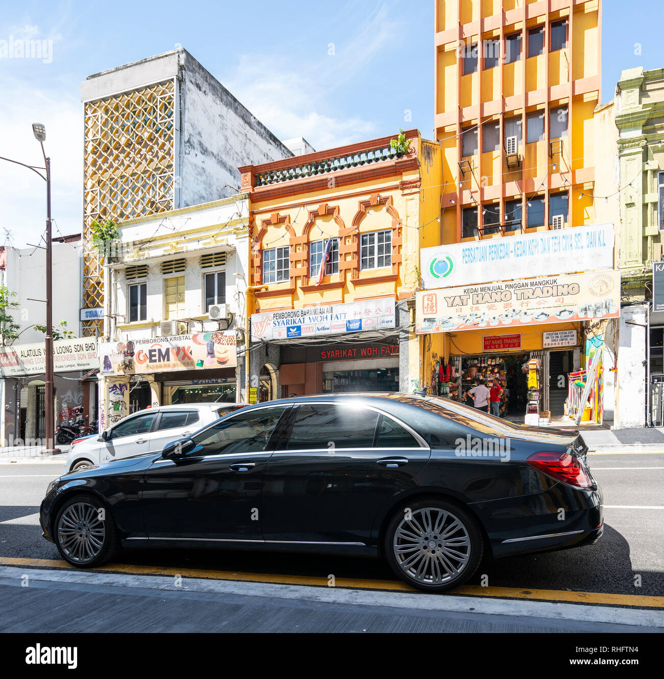 a luxurious car in front of some traditional houses in Kuala Lumpur