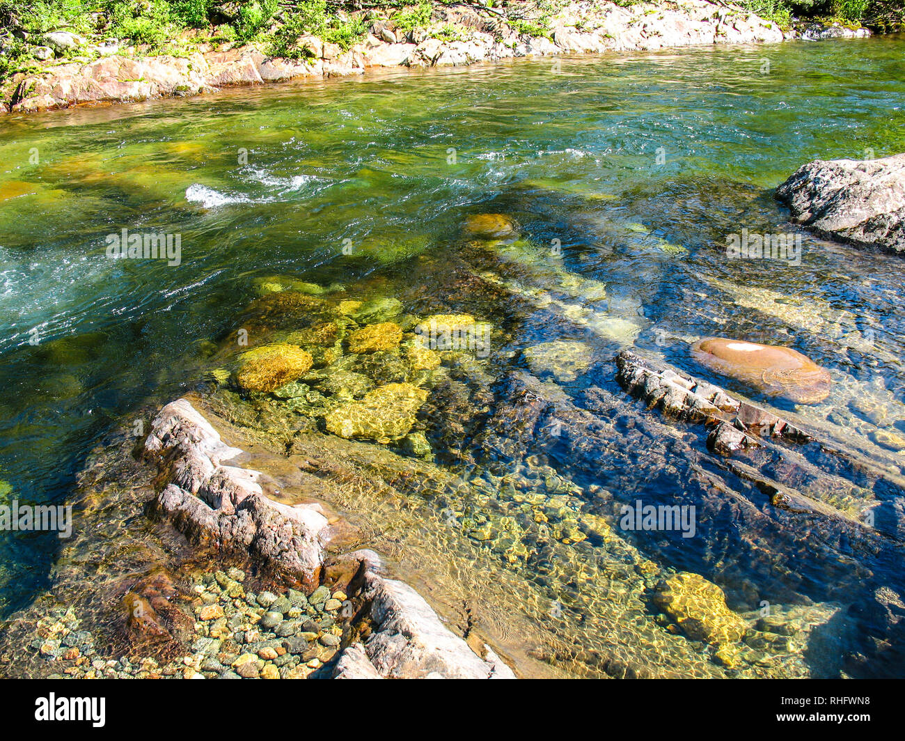 Rapid stream of mountain river with clean transparent water and colorful stones and pebbles on bottom - ecology and environment conservation concept Stock Photo