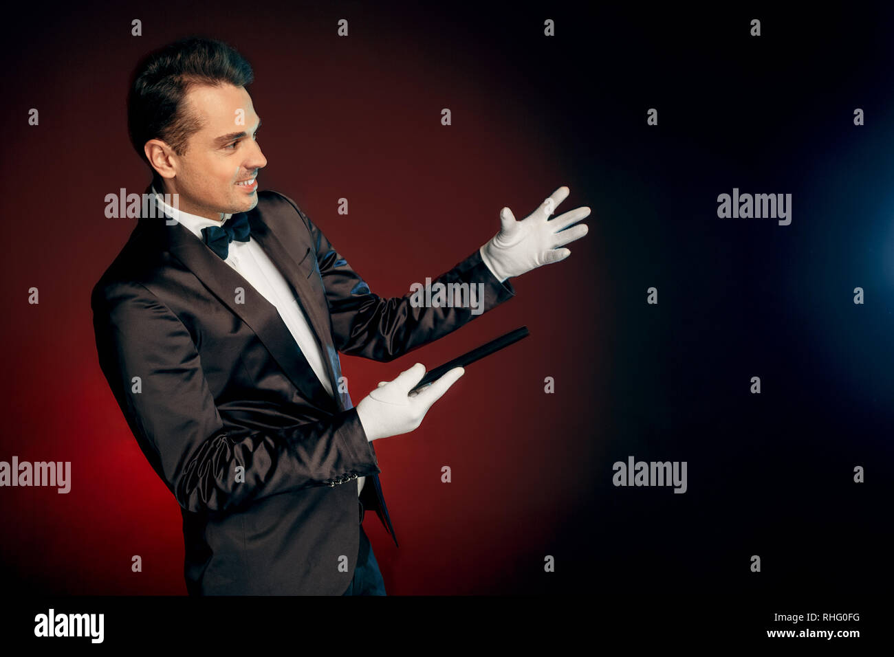 Professional showman wearing suit standing isolated on black and red ...