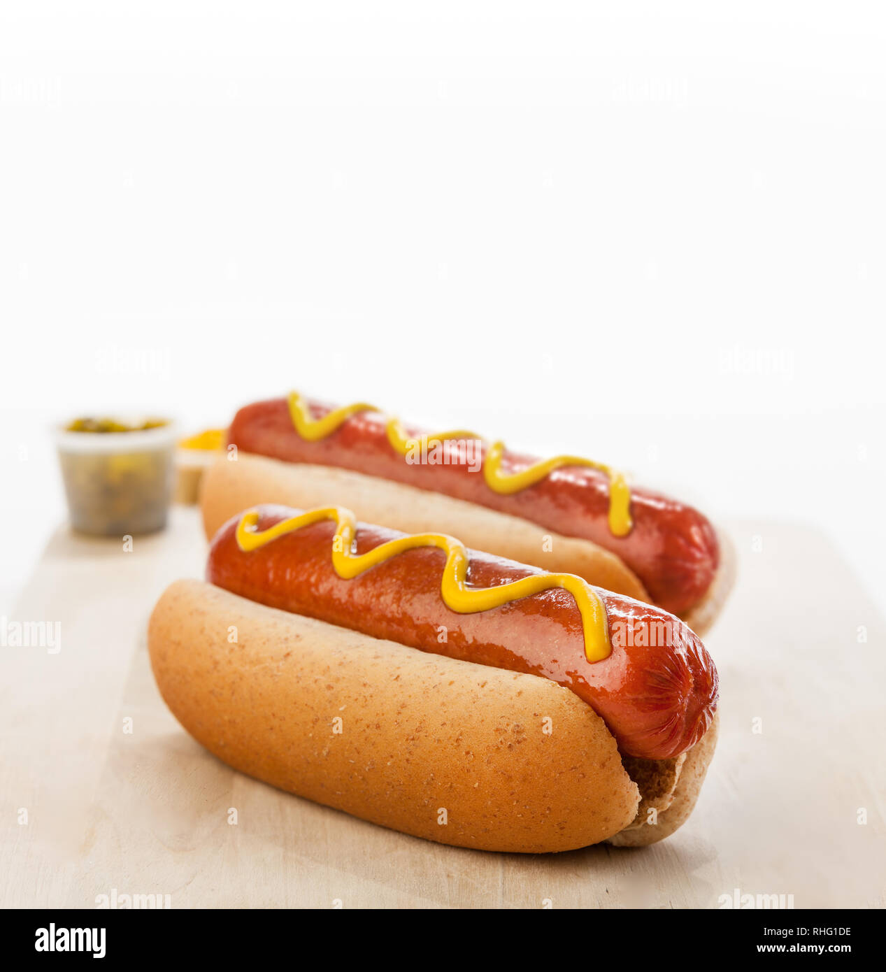 Two giant beefy hot dogs on a bun with mustard and relish Stock Photo