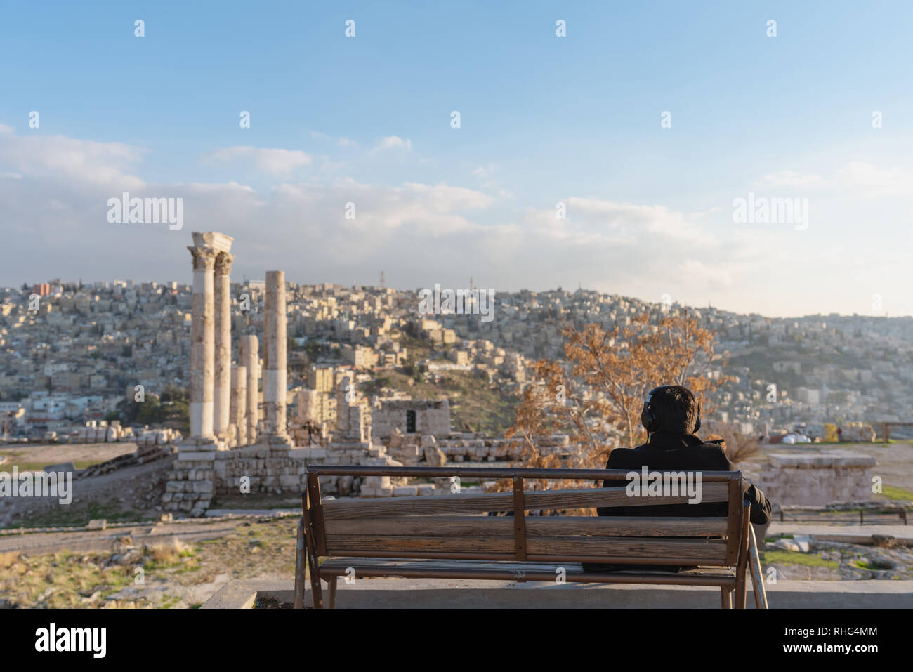 a man sitting alone listening music by headphone at Citadel in Amman, Jordan Stock Photo