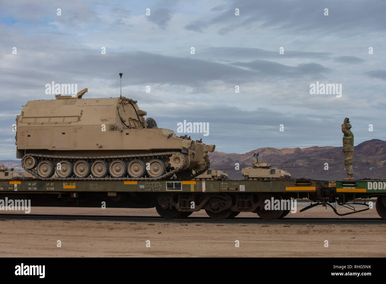 A U.S. Army soldier ground guides a vehicle while conducting rail