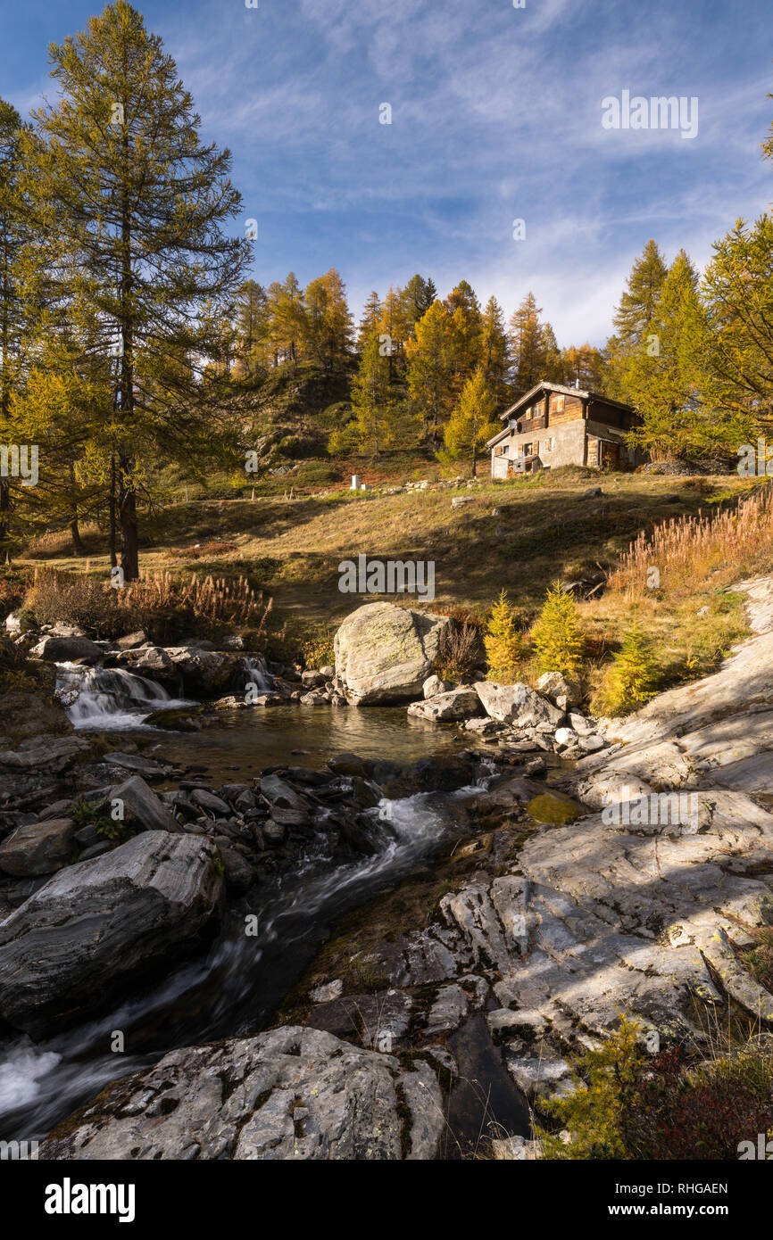 typical mountain hut on the river in the Alps on the Simplonpass road A9 in autumn, Simplon Pass, canton of Valais, Switzerland Stock Photo