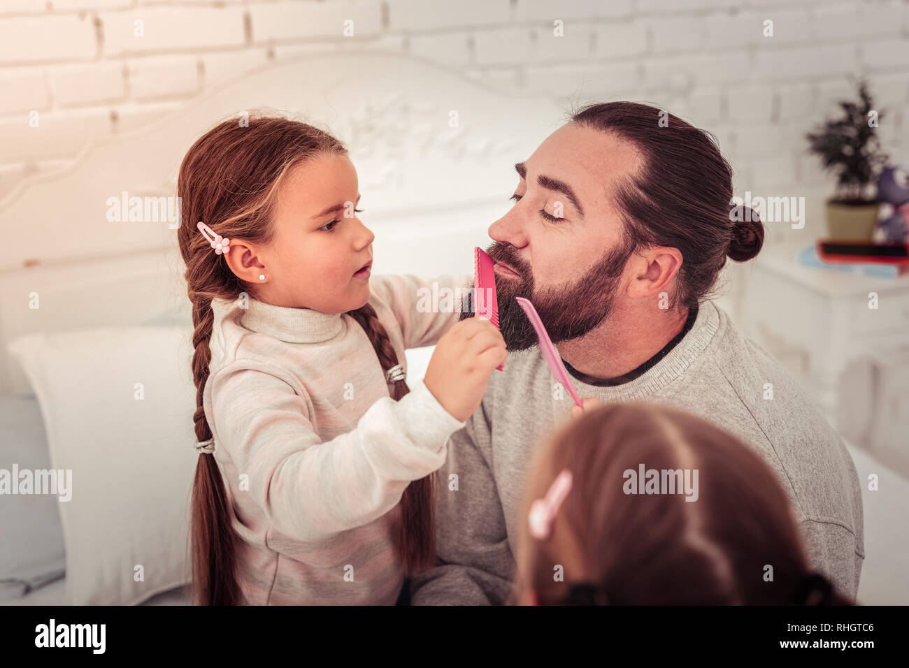 Nice cute girl combing her dads beard Stock Photo