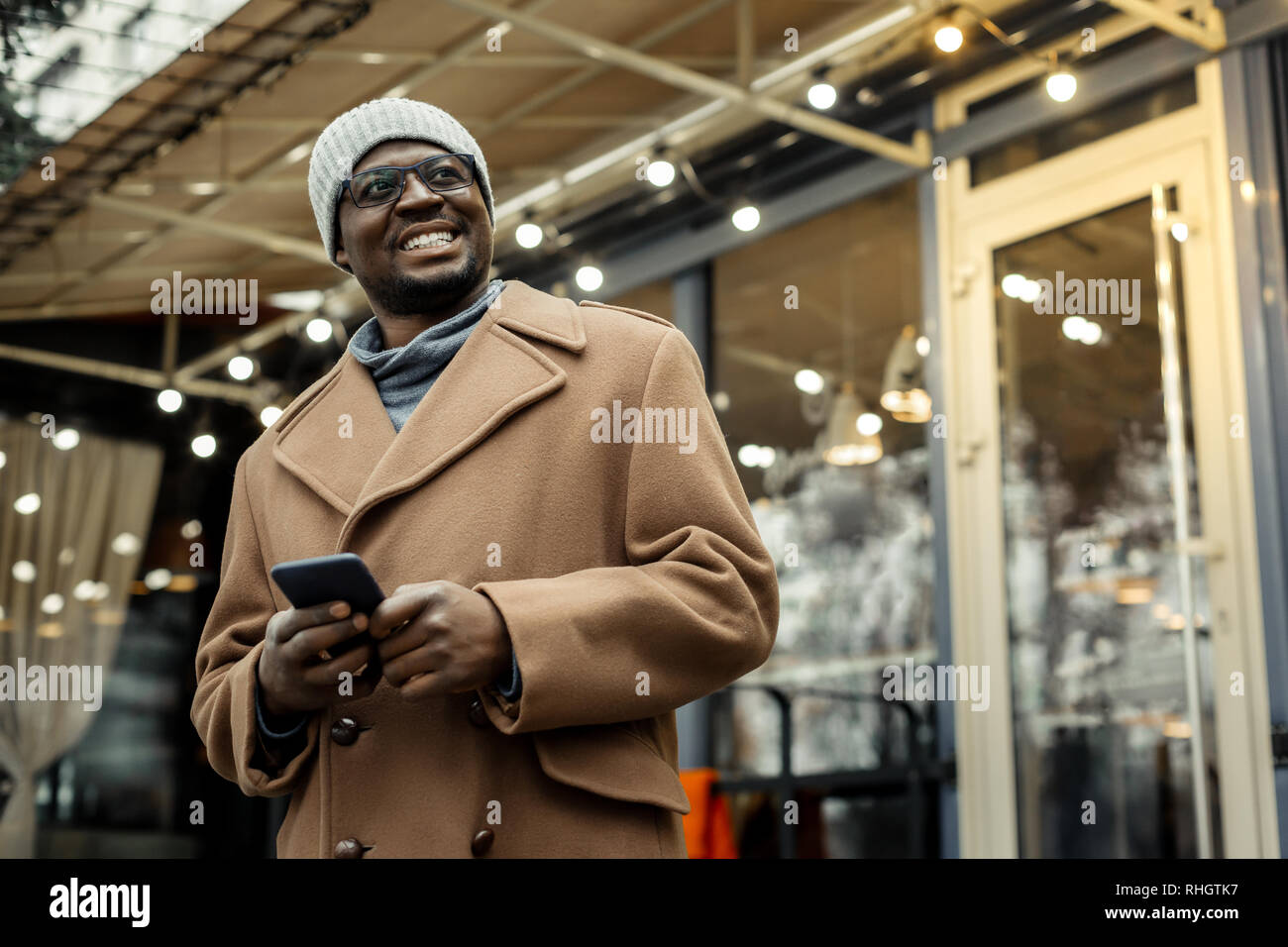 Cheerful handsome African-American man standing outside restaurant Stock Photo
