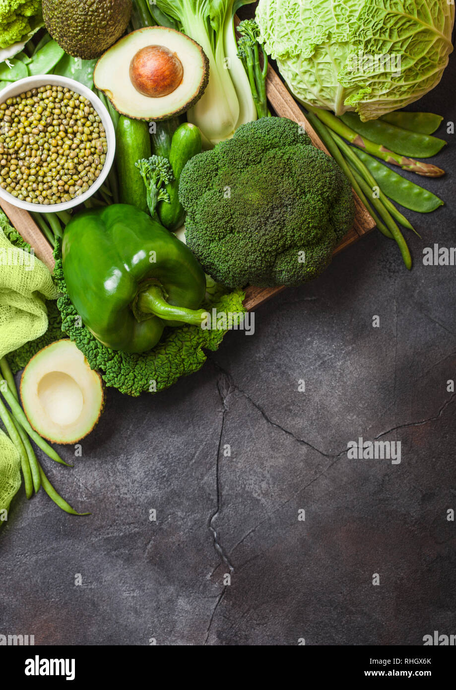 Assorted green toned raw organic vegetables on dark background. Avocado ...