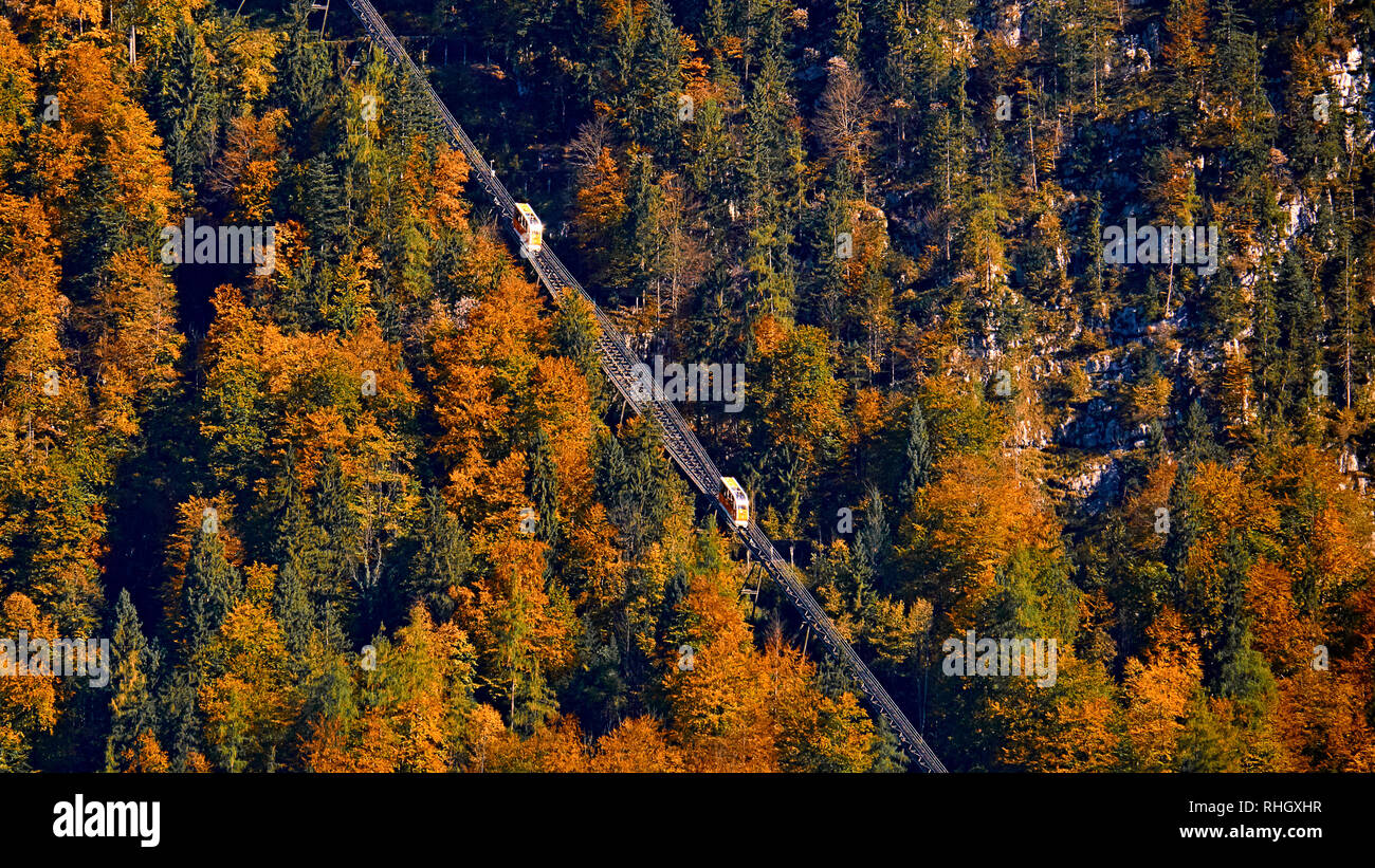 Beautiful aerial fall view of cable car ropeway funicular in austrian alps. Red cable railway car in the mountains by resort village Hallstatt, Salzka Stock Photo