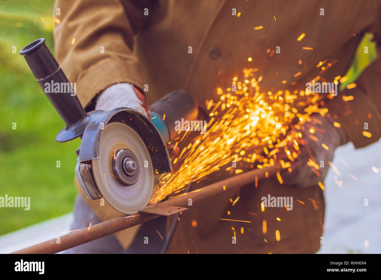 Uniformed worker cuts metal with grinder flying sparks in the process of cutting  rebar Stock Photo - Alamy