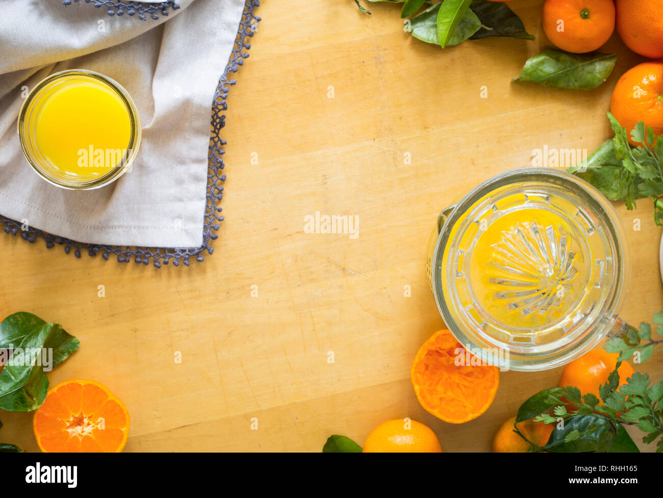overhead view of glass of fresh squeezed orange juice with linens and oranges, with negative space for copy Stock Photo