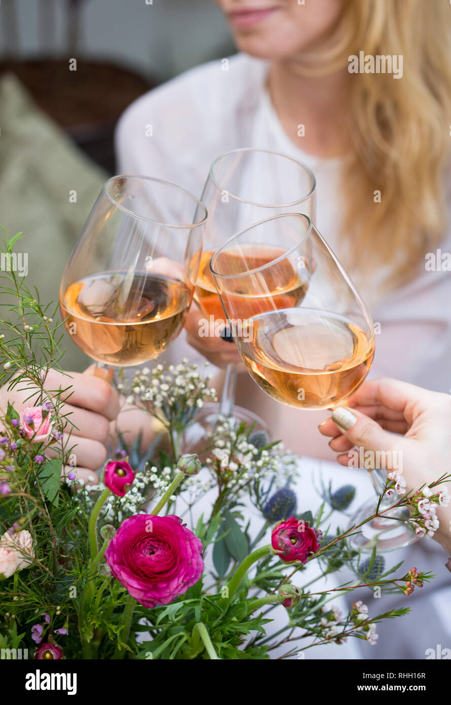 blonde woman toasting friends with wine glasses of rose and flowers Stock Photo