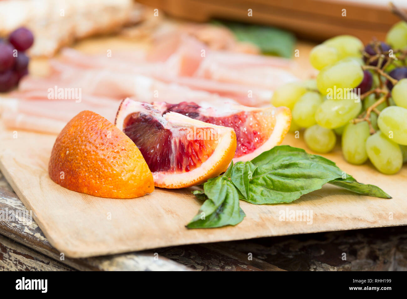 Blood orange slices on wooden charcuterie board for outdoor entertaining picnic. Stock Photo