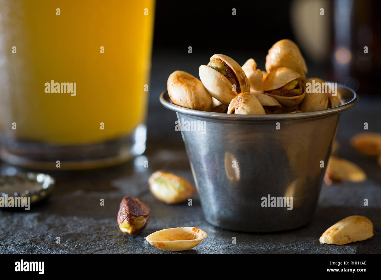 Small cup of pistachios on bar counter with pint glass of craft wheat beer. Stock Photo