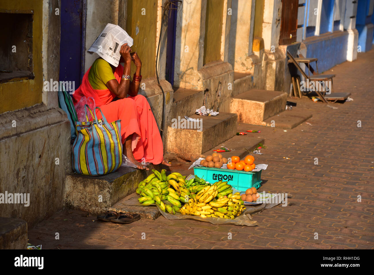 Indian Street Fruit Seller shields from the sun under a newspaper, Panjim, Panaji, Goa, India Stock Photo